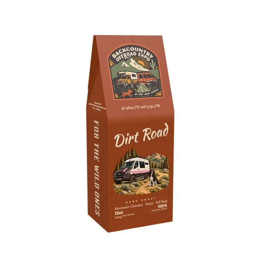 Front of the 12 oz Dirt Road dark-roast coffee box, with Backcountry Offroad Expo branding and a dog beside a pink-striped camper van.